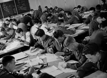 Movie still from “Bombardier” (1943), directed by Lambert Hillyer – Black and white photograph of military men writing; Wide shot, High angle