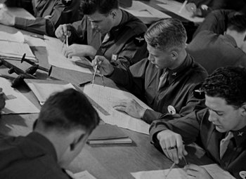 Movie still from “Bombardier” (1943), directed by Lambert Hillyer – Black and white photograph of men writing on papers; Medium shot, High angle