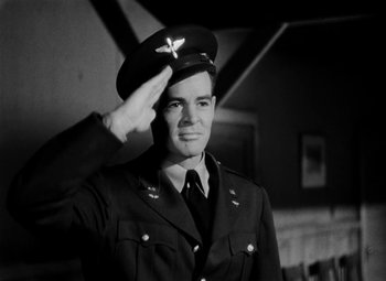 Movie still from “Bombardier” (1943), directed by Lambert Hillyer – A man saluting while wearing an army uniform; Medium shot, Low angle