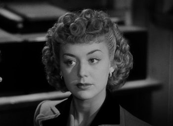 Movie still from “Bombardier” (1943), directed by Lambert Hillyer – A black and white photo of a woman with curly hair; Close Up shot, High angle