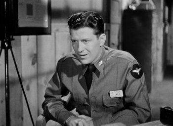 Movie still from “Bombardier” (1943), directed by Lambert Hillyer – A man in uniform sitting in front of a wall; Close Up shot, High angle