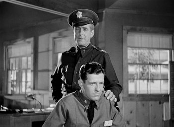 Movie still from “Bombardier” (1943), directed by Lambert Hillyer – A man in uniform sitting next to another man in uniform; Medium shot, Low angle