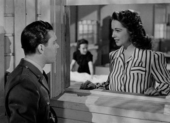 Movie still from “Bombardier” (1943), directed by Lambert Hillyer – A man and a woman looking at each other through a window; Medium shot, Over the shoulder angle