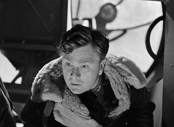 Movie still from “Bombardier” (1943), directed by Lambert Hillyer – Black and white photograph of a man in a jacket; Close Up shot, Low angle