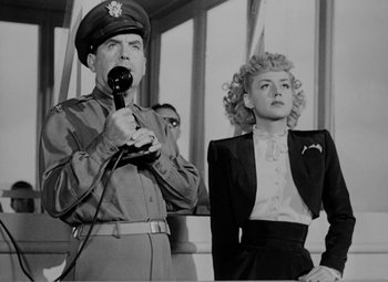 Movie still from “Bombardier” (1943), directed by Lambert Hillyer – An old photo of a man and a woman; Medium shot, Low angle