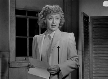 Movie still from “Bombardier” (1943), directed by Lambert Hillyer – A black and white photo of a woman holding a piece of paper; Medium shot, Low angle