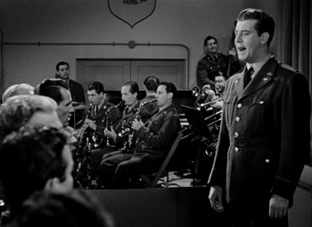 Movie still from “Bombardier” (1943), directed by Lambert Hillyer – A group of men in military uniforms playing instruments; Medium shot, Low angle