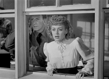 Movie still from “Bombardier” (1943), directed by Lambert Hillyer – An old photo of a man and a woman looking out of a window; Medium shot, Over the shoulder angle