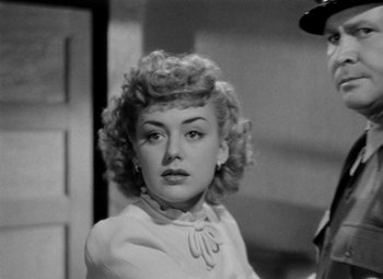 Movie still from “Bombardier” (1943), directed by Lambert Hillyer – A black - and - white photo of a woman in a white dress; Close Up shot, Over the shoulder angle