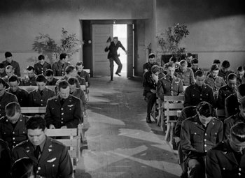 Movie still from “Bombardier” (1943), directed by Lambert Hillyer – A group of men in uniform sitting in rows; Wide shot, High angle