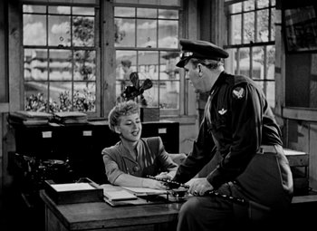 Movie still from “Bombardier” (1943), directed by Lambert Hillyer – An old photo of two people sitting at a desk; Wide shot, Low angle