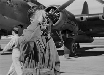Movie still from “Bombardier” (1943), directed by Lambert Hillyer – An old photo of a man talking on a cell phone in front of an airplane; Medium shot, Low angle