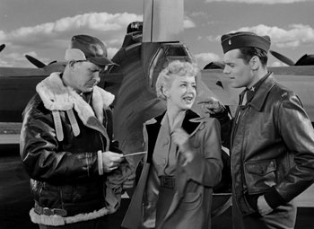 Movie still from “Bombardier” (1943), directed by Lambert Hillyer – An old photo of a man and a woman and another man; Medium shot, Over the shoulder angle