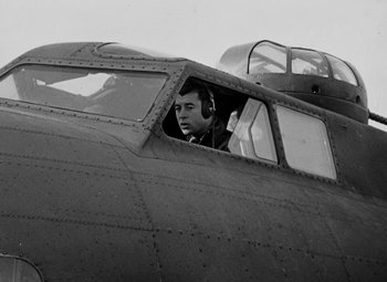 Movie still from “Bombardier” (1943), directed by Lambert Hillyer – A man sitting inside of an airplane looking out of the window; Medium shot, Low angle