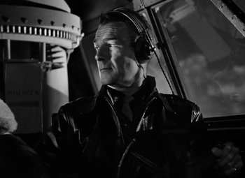 Movie still from “Bombardier” (1943), directed by Lambert Hillyer – An older man wearing a leather jacket and ear muffs; Medium shot, Low angle