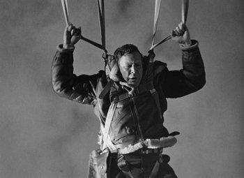 Movie still from “Bombardier” (1943), directed by Lambert Hillyer – A man is flying a hot air balloon in the sky; Medium shot, Low angle