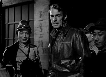 Movie still from “Bombardier” (1943), directed by Lambert Hillyer – A man in a leather jacket standing next to another man in a military uniform; Medium shot, Over the shoulder angle