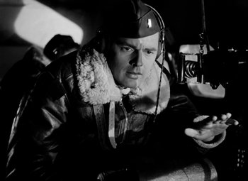 Movie still from “Bombardier” (1943), directed by Lambert Hillyer – A man in a helmet and a jacket is looking at a camera; Close Up shot, Low angle