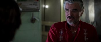 Movie still from “Boogie Nights” (1997), directed by Paul Thomas Anderson – An older man with a gray beard wearing a red shirt; Close Up shot, Over the shoulder angle