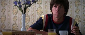 Movie still from “Boogie Nights” (1997), directed by Paul Thomas Anderson – A man sitting at a table with a glass of orange juice in front of him; Close Up shot, Low angle