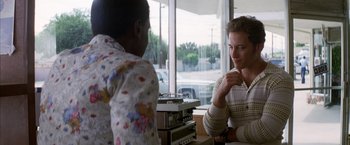 Movie still from “Boogie Nights” (1997), directed by Paul Thomas Anderson – Two men sitting at a table talking to each other; Medium shot, Over the shoulder angle