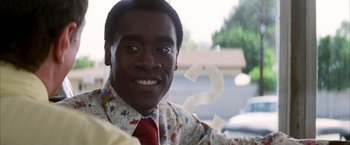 Movie still from “Boogie Nights” (1997), directed by Paul Thomas Anderson – A man in a floral shirt smiles for the camera; Close Up shot, Over the shoulder angle