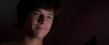 Movie still from “Boogie Nights” (1997), directed by Paul Thomas Anderson – A young man smiling for the camera; Close Up shot, Low angle