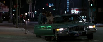 Movie still from “Boogie Nights” (1997), directed by Paul Thomas Anderson – Two people standing next to a car on the side of the road; Wide shot, Over the shoulder angle
