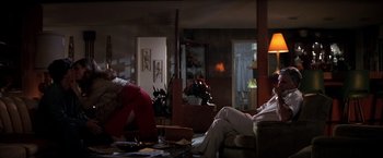 Movie still from “Boogie Nights” (1997), directed by Paul Thomas Anderson – Two people sitting in a living room next to each other; Wide shot, Over the shoulder angle