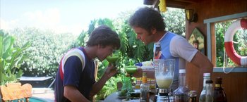 Movie still from “Boogie Nights” (1997), directed by Paul Thomas Anderson – Two men are having a drink at a table; Medium shot, High angle