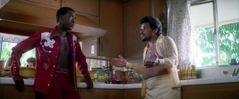 Movie still from “Boogie Nights” (1997), directed by Paul Thomas Anderson – Two men are talking in the kitchen together; Medium shot, Low angle