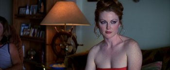 Movie still from “Boogie Nights” (1997), directed by Paul Thomas Anderson – A woman in a strapless red dress sitting in front of a lamp; Close Up shot, Over the shoulder angle