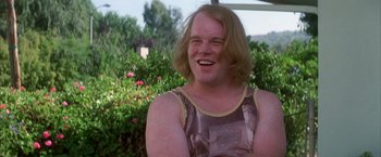 Movie still from “Boogie Nights” (1997), directed by Paul Thomas Anderson – A man with blonde hair is smiling for the camera; Close Up shot, Over the shoulder angle