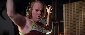 Movie still from “Boogie Nights” (1997), directed by Paul Thomas Anderson – A man with a beard is wearing headphones and posing for a picture; Close Up shot, Low angle