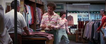 Movie still from “Boogie Nights” (1997), directed by Paul Thomas Anderson – A man in a shirt is looking at his cell phone; Medium shot, Over the shoulder angle