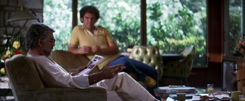 Movie still from “Boogie Nights” (1997), directed by Paul Thomas Anderson – A man sitting in front of another man holding a book; Medium shot, Over the shoulder angle