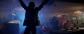 Movie still from “Boogie Nights” (1997), directed by Paul Thomas Anderson – A man standing in front of an audience at a party; Wide shot, Low angle