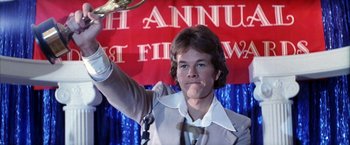 Movie still from “Boogie Nights” (1997), directed by Paul Thomas Anderson – A man holding a tennis racquet in front of a crowd; Close Up shot, Low angle