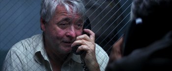 Movie still from “Boogie Nights” (1997), directed by Paul Thomas Anderson – An older man talking on a phone in front of a fence; Close Up shot, High angle
