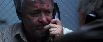 Movie still from “Boogie Nights” (1997), directed by Paul Thomas Anderson – An older man talking on a cell phone in front of a chain link fence; Close Up shot, Low angle