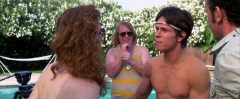 Movie still from “Boogie Nights” (1997), directed by Paul Thomas Anderson – A woman and two men standing next to each other near a swimming pool; Close Up shot, Over the shoulder angle