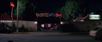 Movie still from “Boogie Nights” (1997), directed by Paul Thomas Anderson – A motel sign lit up at night in the dark; Wide shot, Low angle