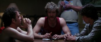 Movie still from “Boogie Nights” (1997), directed by Paul Thomas Anderson – A man sitting at a table with a cigarette in his mouth; Medium shot, Low angle