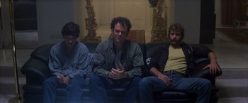 Movie still from “Boogie Nights” (1997), directed by Paul Thomas Anderson – A group of men sitting on a couch; Medium shot, Low angle