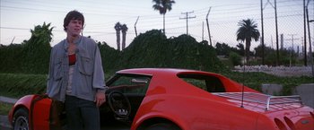 Movie still from “Boogie Nights” (1997), directed by Paul Thomas Anderson – A man standing in front of a red sports car; Medium shot, Low angle