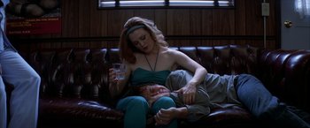 Movie still from “Boogie Nights” (1997), directed by Paul Thomas Anderson – A woman sitting on a man's lap holding a drink; Medium shot, Overhead angle