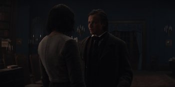 Movie still from “Dark” (2017), created by Baran bo Odar – A man and a woman standing next to each other in front of lights; Medium shot, Over the shoulder angle