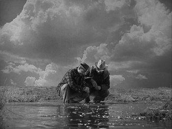 Movie still from “Boom Town” (1940), directed by Jack Conway – Two men are standing in shallow water looking at the sky; Wide shot, High angle