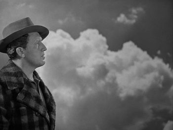 Movie still from “Boom Town” (1940), directed by Jack Conway – A black and white photo of a man in a hat looking up at the sky; Medium shot, Low angle