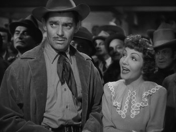 Movie still from “Boom Town” (1940), directed by Jack Conway – A man and a woman standing next to each other in a crowd; Medium shot, Low angle